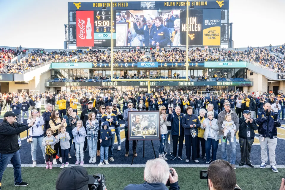 Don Nehlen is surrounded by friends and family on Mountaineer Field while he's honored.