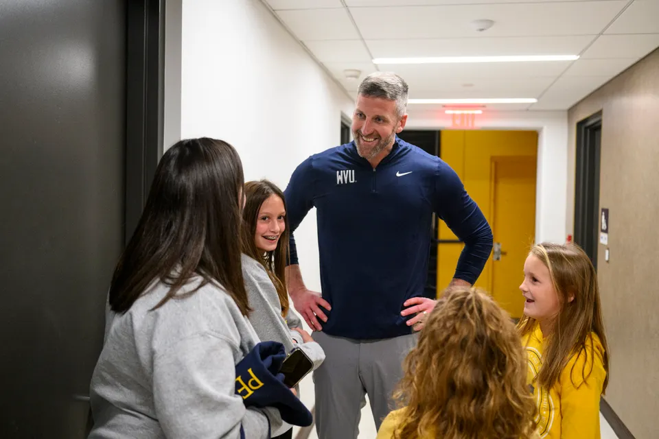 West Virginia interim coach Josh Eilert talks with young fans in a hallway before his coaching debut.