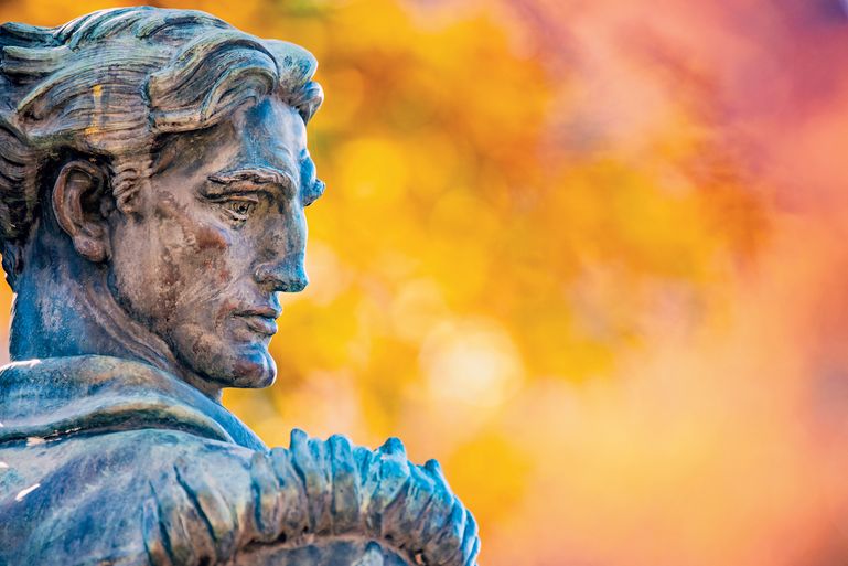mountaineer statue face looking over shoulder, fall leaves in background