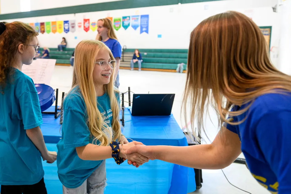 a younger and older student shake hands