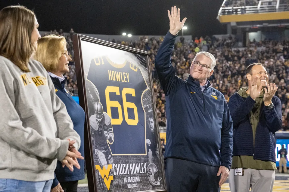 Chuck Howley waves to the crowd as he stands next to a framed West Virginia jersey with the number 66 on it.