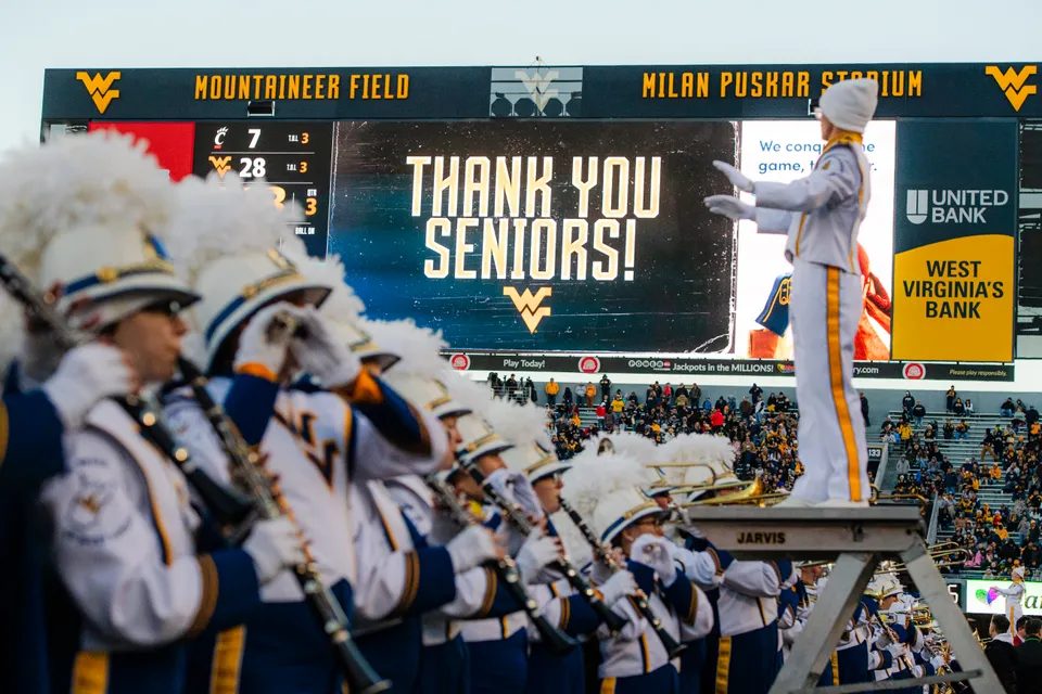 "Thank You Seniors" is displayed on the Milan Puskar Stadium jumbo screen as The Pride of West Virginia performs on the field.
