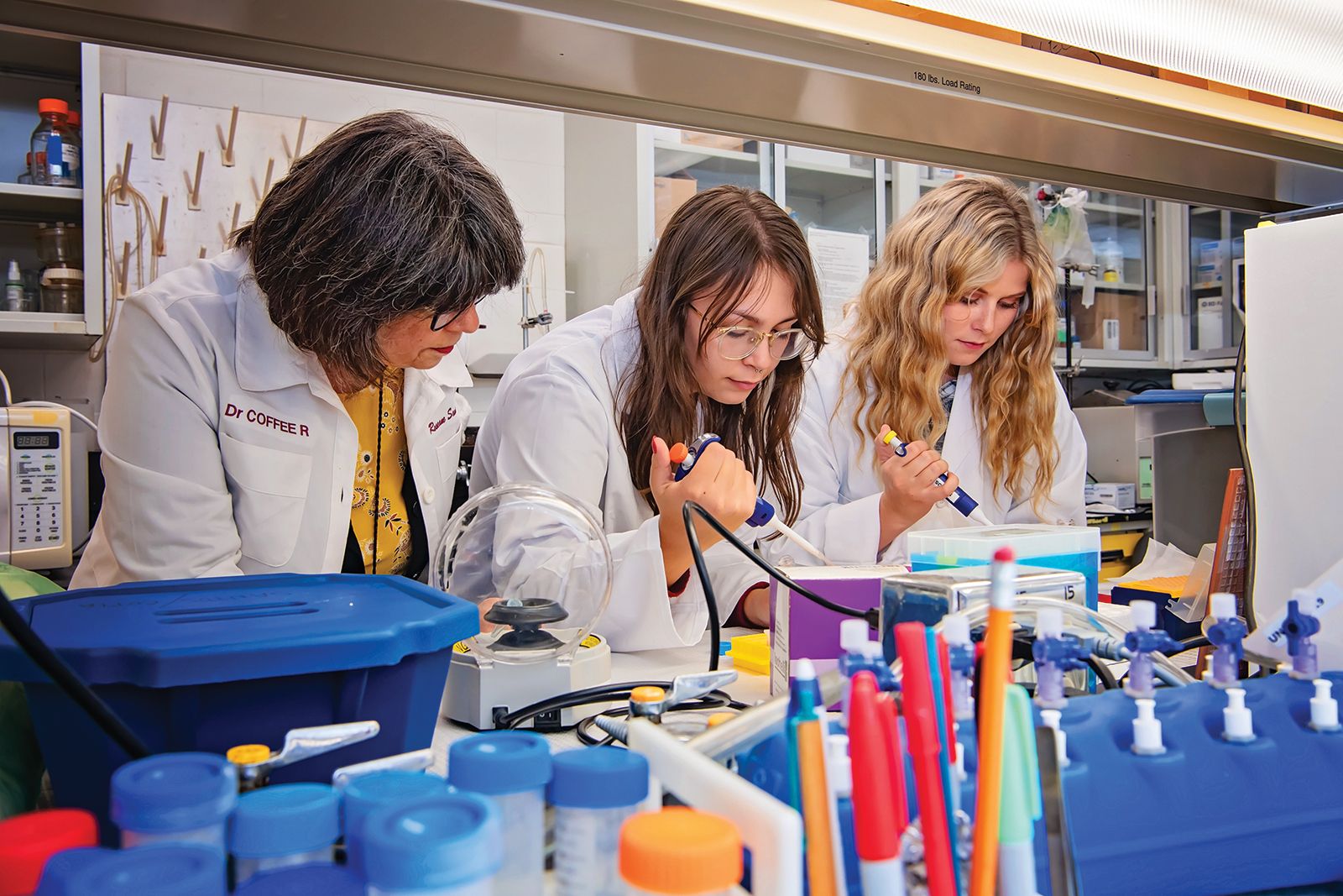 Three women in labcoats work in lab